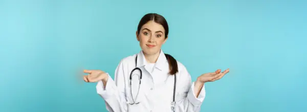 Portrait doctor woman intern shrugging shoulders smiling saying sorry dont know being clueles